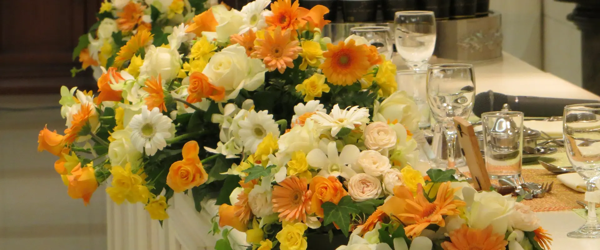イエローとオレンジの花を使った高砂席のブライダル装花